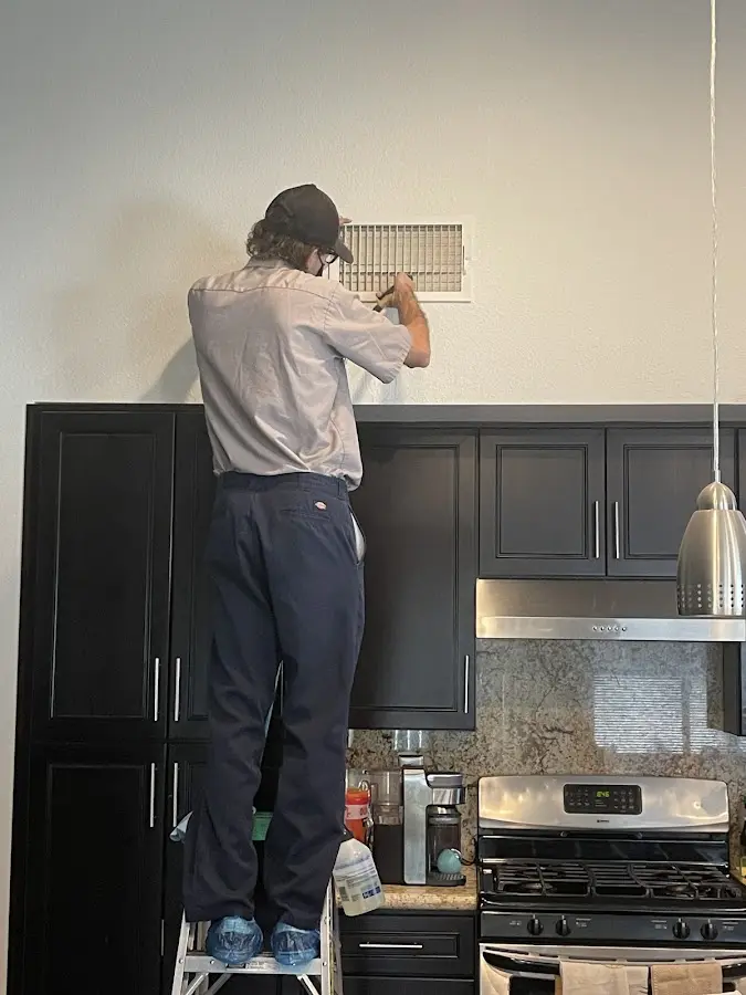 Technician inspecting an air vent during HVAC service in Sierra Vista